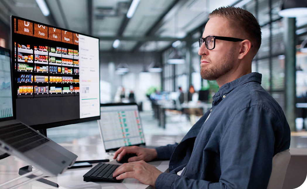 A man is sitting at a desk using a laptop. Description generated by AI