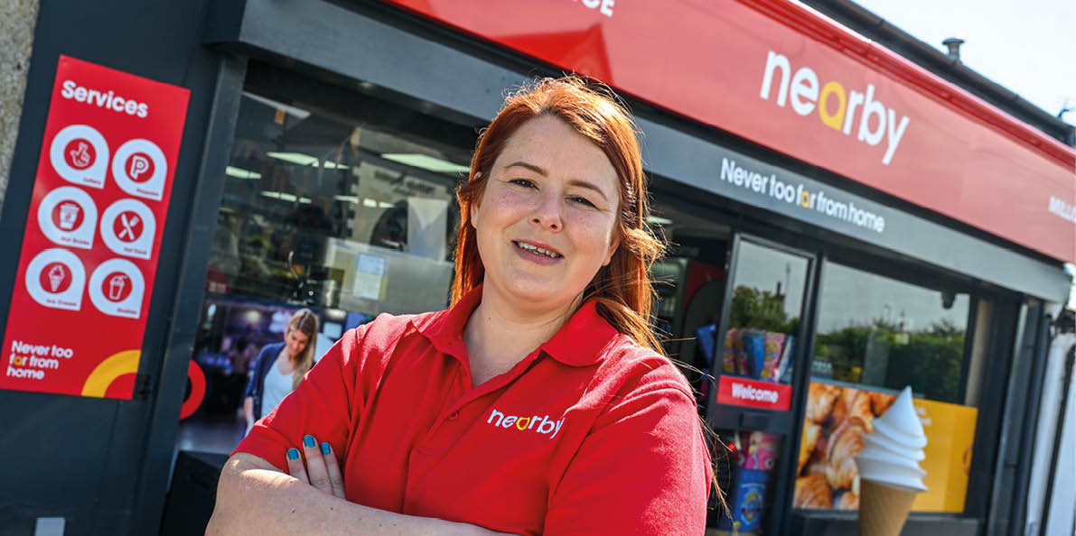 A woman wearing a red shirt and standing in front of a store. Description generated by AI