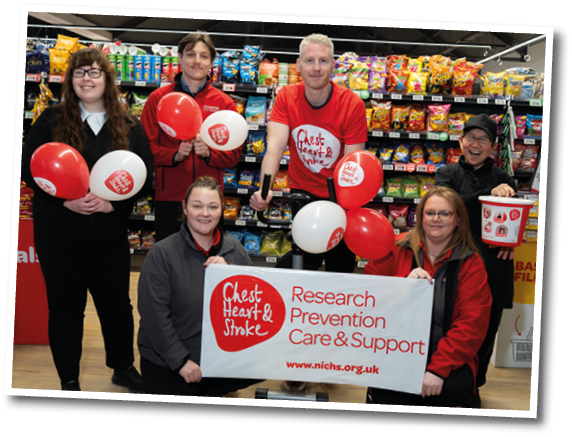 A group of people are posing for a picture in front of a sign that says “Clothes Heart & Prevention Care & Support." Description generated by AI