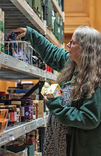 A woman in a green sweater is reaching for a box of tea. Description generated by AI