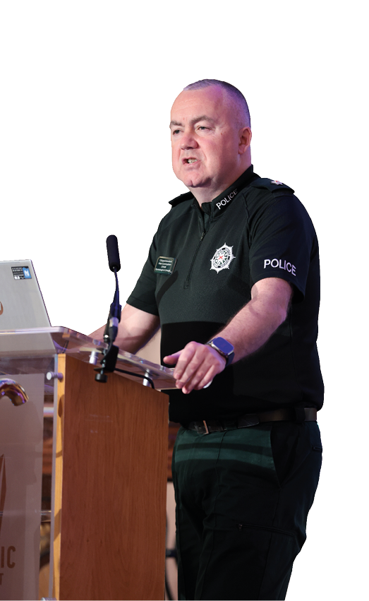A man wearing a green shirt and black pants is standing at a podium. Description generated by AI