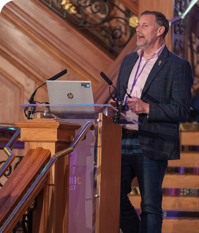 A man standing in front of a podium. Description generated by AI