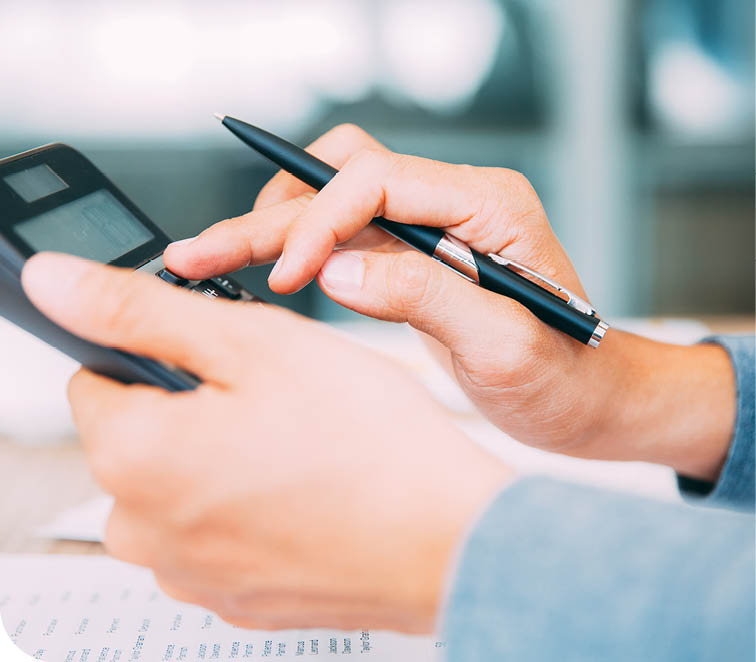 A person is using a calculator and pen to write numbers. Description generated by AI