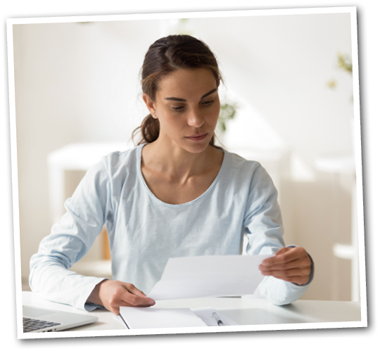 A woman in a blue shirt is reading a piece of paper. Description generated by AI