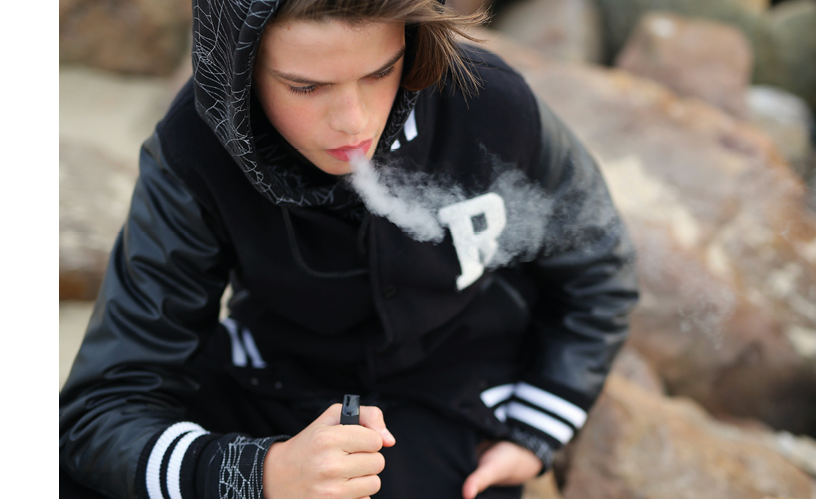 A boy smoking a cigarette. Description generated by AI