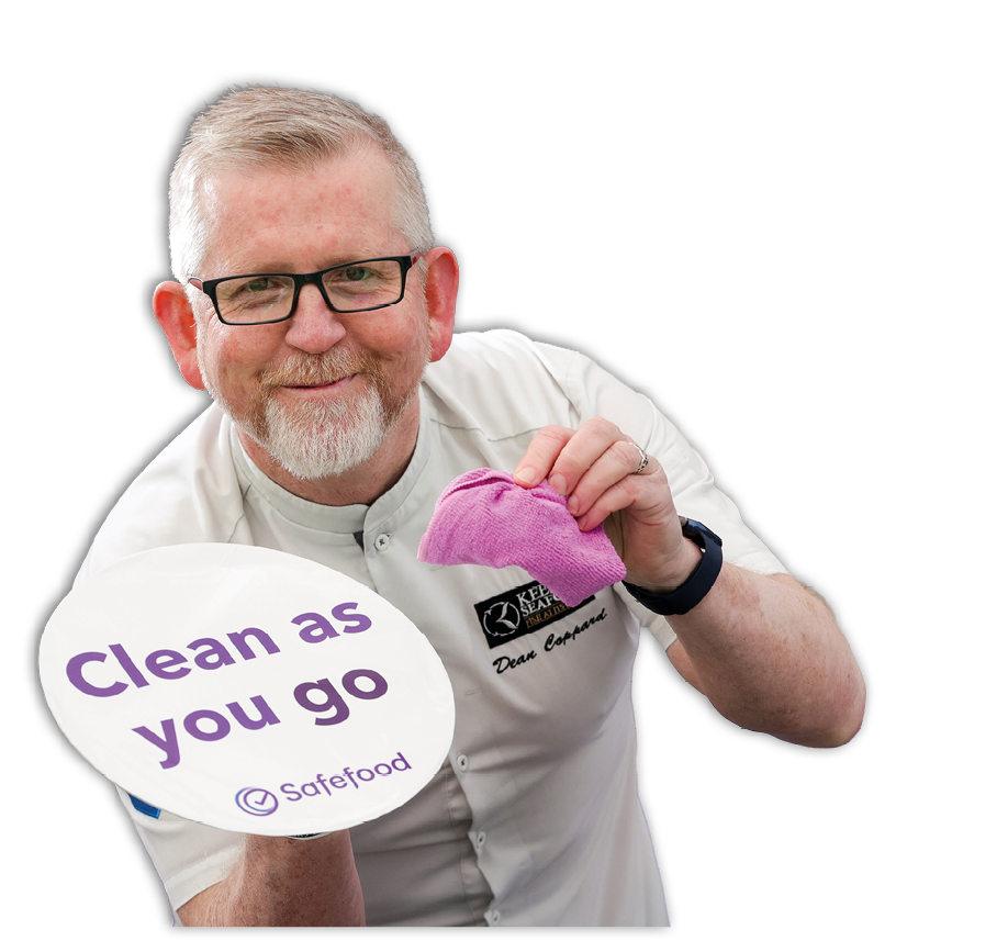 A man holding a pink sign that says “clean as you go". Description generated by AI