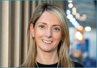 A woman with blonde hair and a black shirt. Description generated by AI