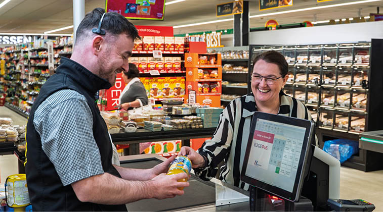 A man is holding a can of soda in front of a cash register. Description generated by AI