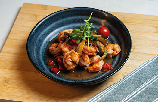 A plate of food with a tomato, peppers, and shrimp. Description generated by AI