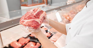 A person is holding a piece of raw meat in a grocery store. Description generated by AI