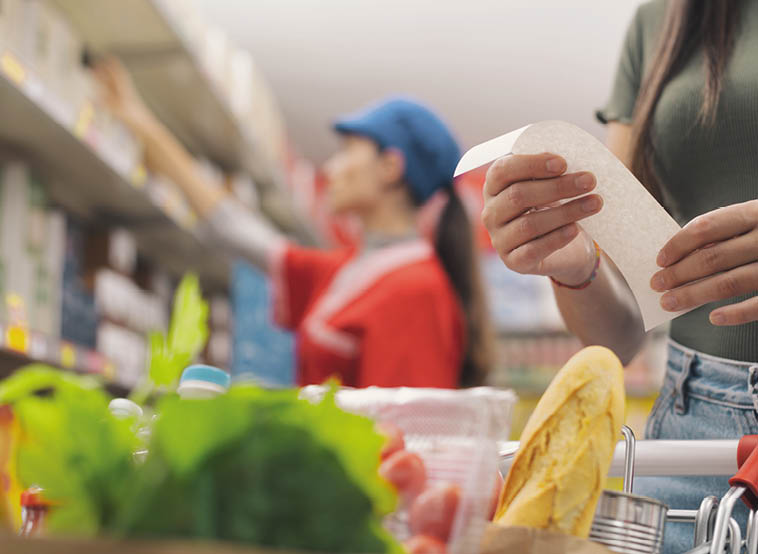 A woman holding a piece of paper in a grocery store. Description generated by AI