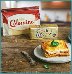 A table with a plate of food and a box of cheese. Description generated by AI