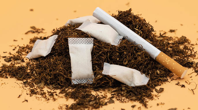 a pile of tobacco with a cigarette and nicotine sachets. 