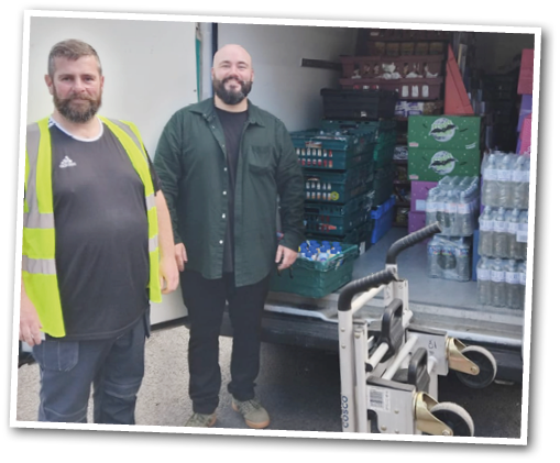 Two adults stand next to an open delivery van filled with stacked crates and bottled water, with a hand truck positioned nearby. Description generated by AI