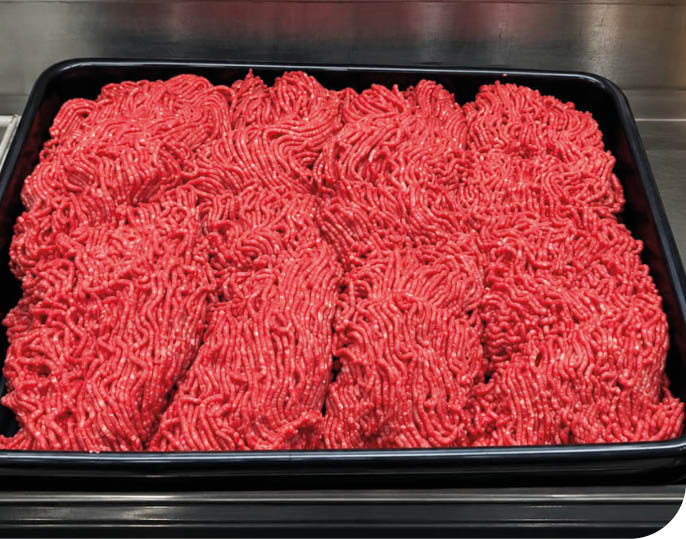 A black tray filled with neatly arranged raw ground meat strands on a metal surface. Description generated by AI