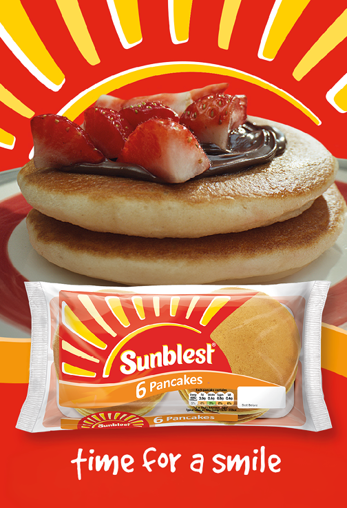 Two stacked pancakes topped with chocolate spread and sliced strawberries are shown above a package of Sunblest 6 Pancakes with the phrase time for a smile on a red and yellow background. Description generated by AI
