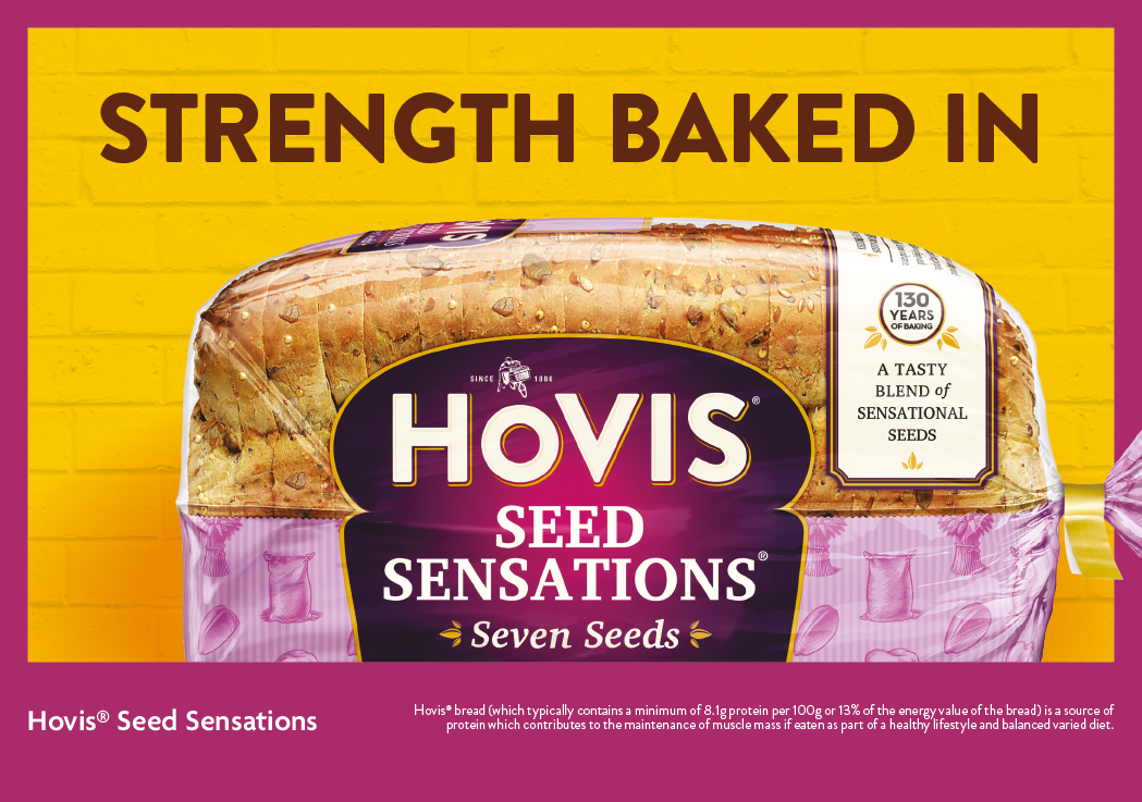 A loaf of Hovis Seed Sensations Seven Seeds bread is displayed against a yellow brick wall background with the text “Strength Baked In" above it. Description generated by AI