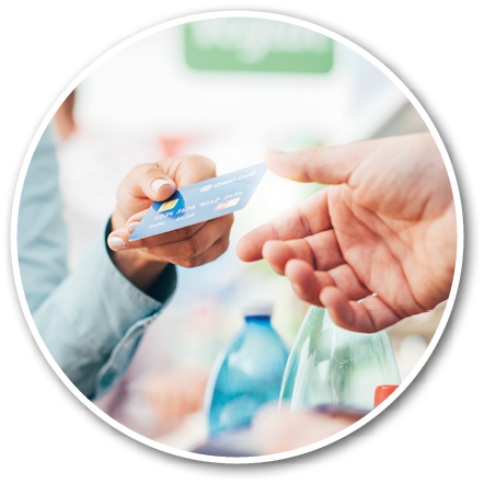 A person is handing a credit card to another person across a counter with blurred bottles in the background. Description generated by AI
