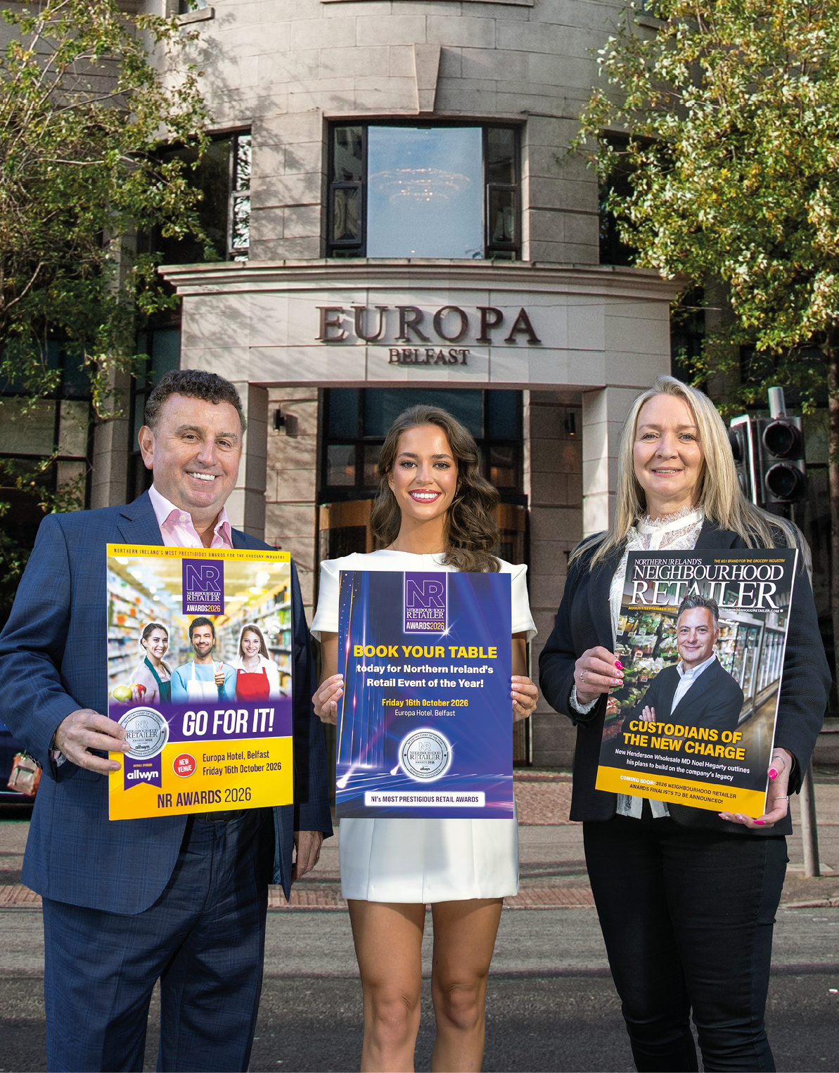 Three adults dressed in business attire stand outside a building labeled Europa Belfast holding promotional posters for retail awards and events. Description generated by AI