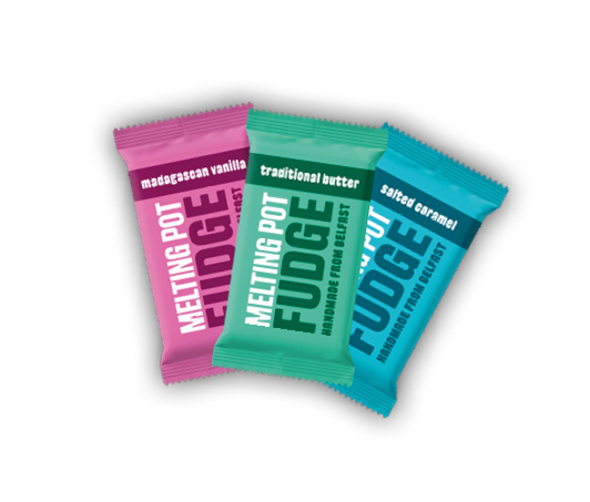 Three colorful wrapped bars of melting pot fudge in flavors Madagascar vanilla, traditional butter, and salted caramel. Description generated by AI