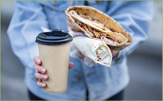 A young woman holding a glass of coffee and fast food. Close up. The concept of fast food .