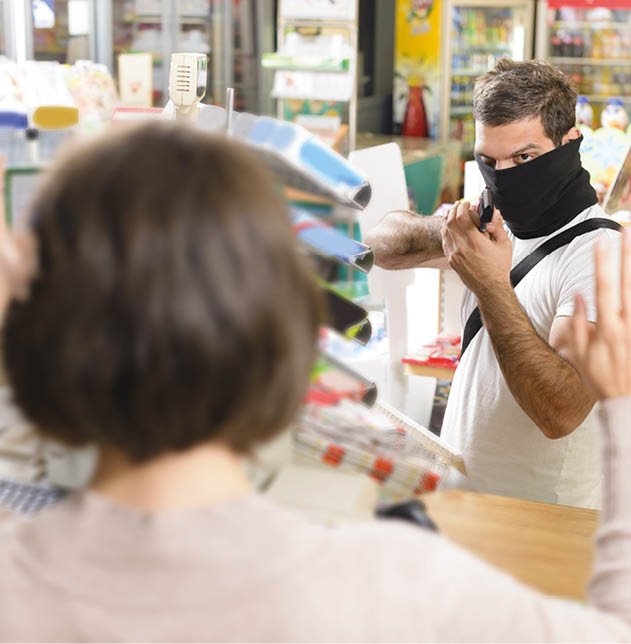 Masked thief pointing a gun to sales woman in a store