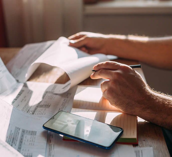 Close-up of men's hands with a calculator and utility bills. The concept of rising prices for heating, gas, and electricity. Lots of utility bills and hands with a calculator and a notebook