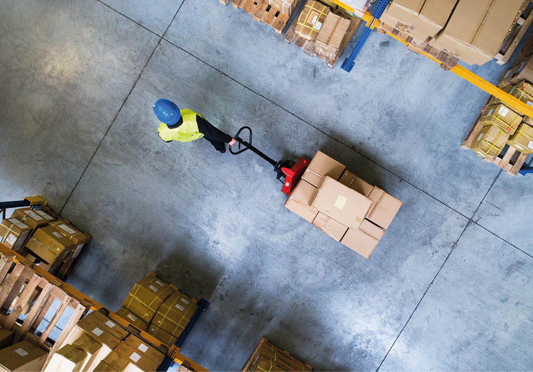 Male warehouse worker pulling a pallet truck.