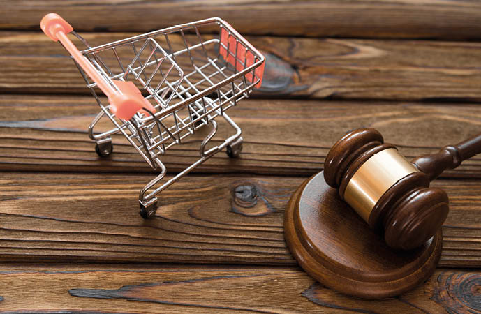 hammer of the judge, a trolley from a supermarket on a wooden background. consumer rights Protection.