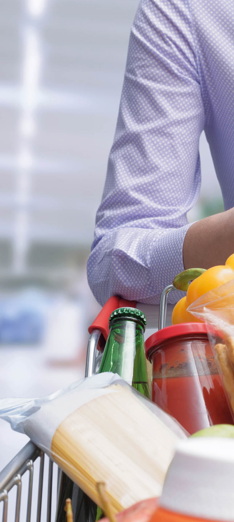 Woman pushing a cart and checking a grocery receipt, grocery shopping and expenses concept