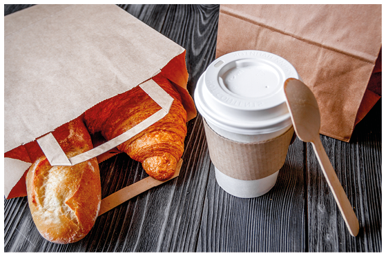 cup coffee and croissant in paper bag on wooden background