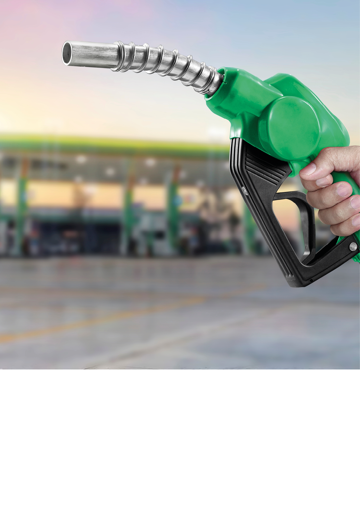 Holding a fuel nozzle against with gas station blurred background