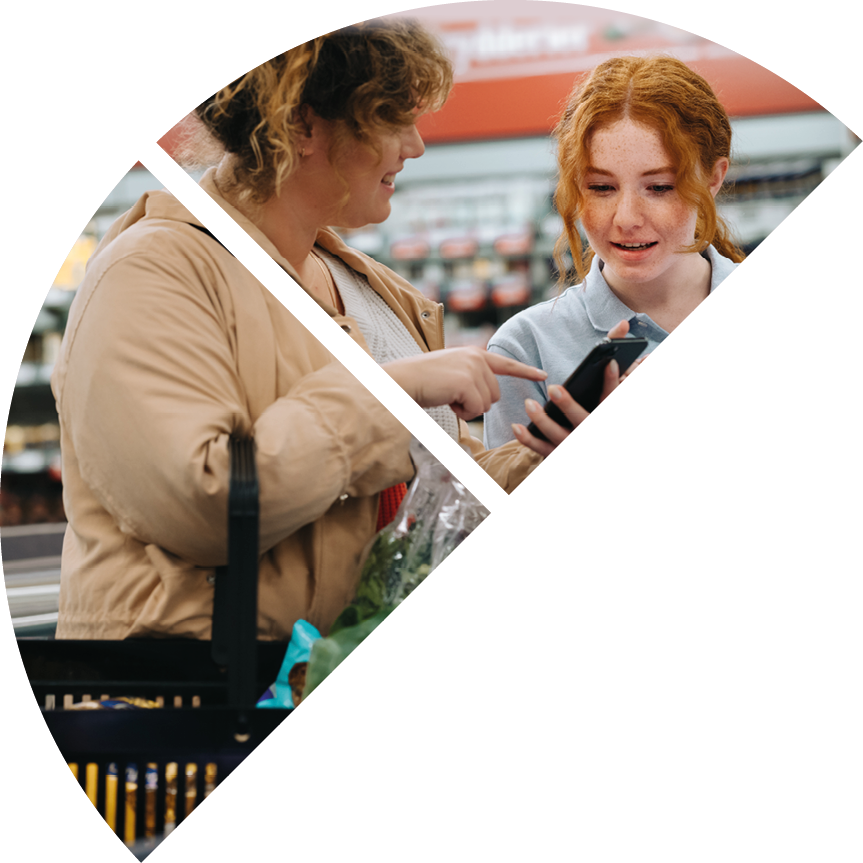 Grocery store worker assisting female shopper. Female customer showing her mobile phone to store assistant and asking for the product at supermarket.