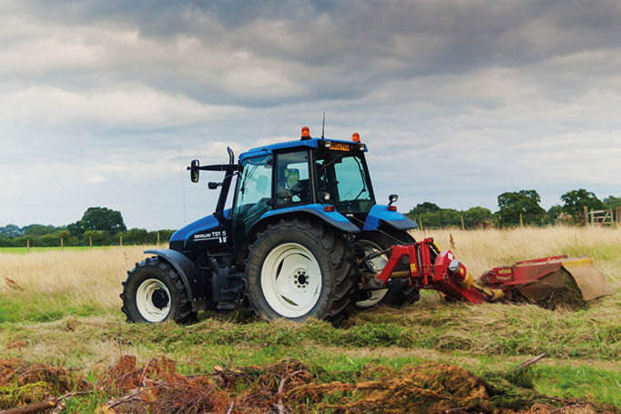Dudleston Shropshire UK - 10 July 2010: Farmer cutting hay from meadow using topper prior to rainfall.