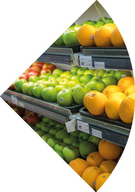 Fresh healthy fruits on shelves in supermarket. With a woman hand choosing best fruits