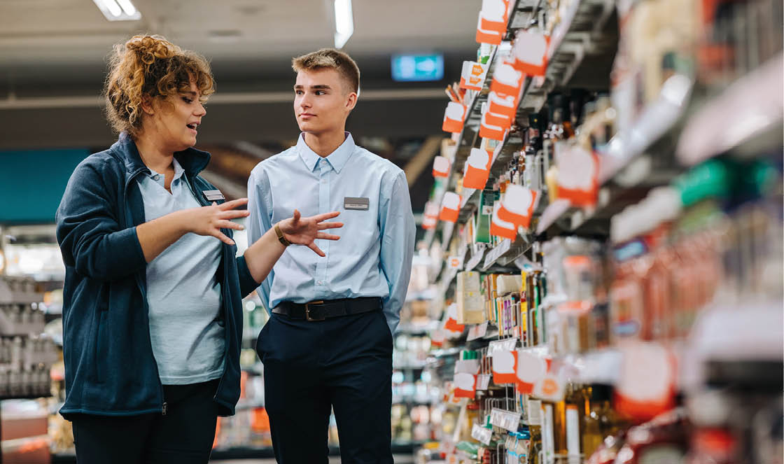 Store manager training young worker. Supermarket manager giving training to a trainee.