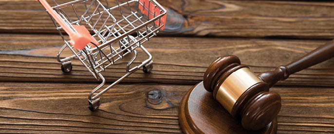 hammer of the judge, a trolley from a supermarket on a wooden background. consumer rights Protection.