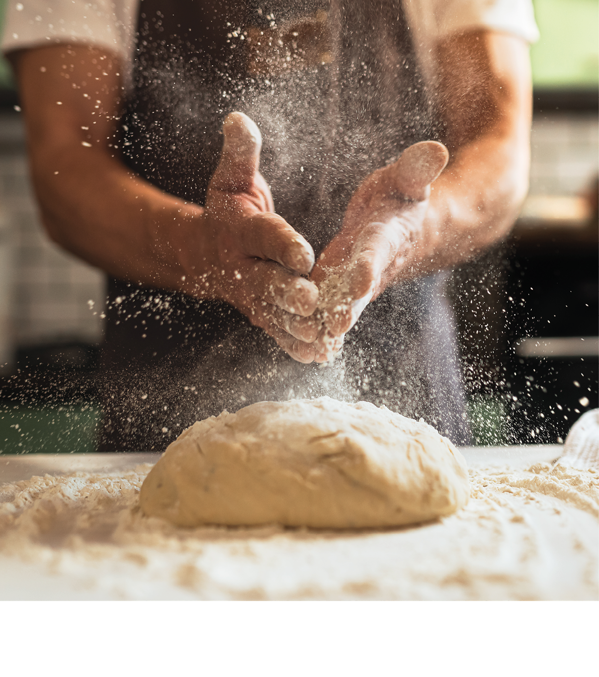 Kneading dough. Male chef in kitchen chef's apron spraying flour over dough