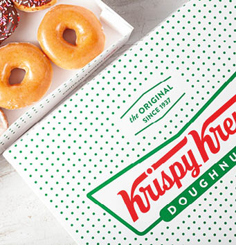 Columbus, OH,USA 02-09-2022: Closeup isolated image assorted Krispy Kreme doughnuts in brand name dozen box. On the box it says “contains a dozen smiles" A favorite donut brand in USA