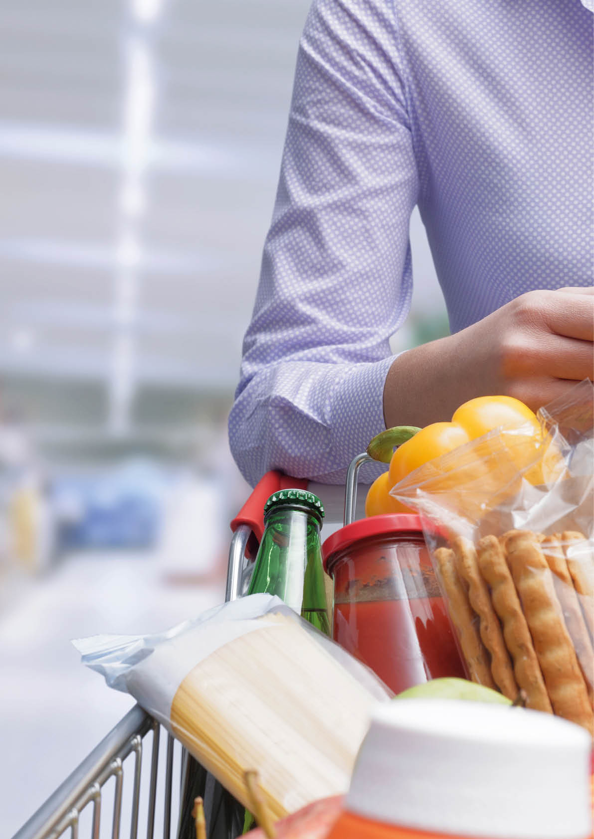 Woman pushing a cart and checking a grocery receipt, grocery shopping and expenses concept
