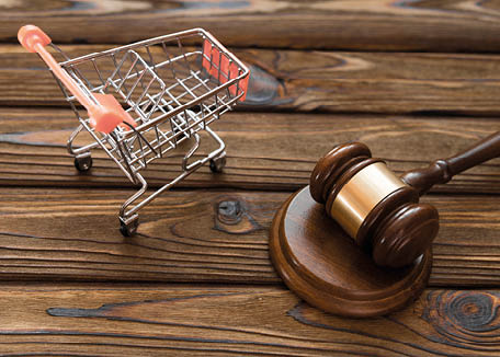 hammer of the judge, a trolley from a supermarket on a wooden background. consumer rights Protection.